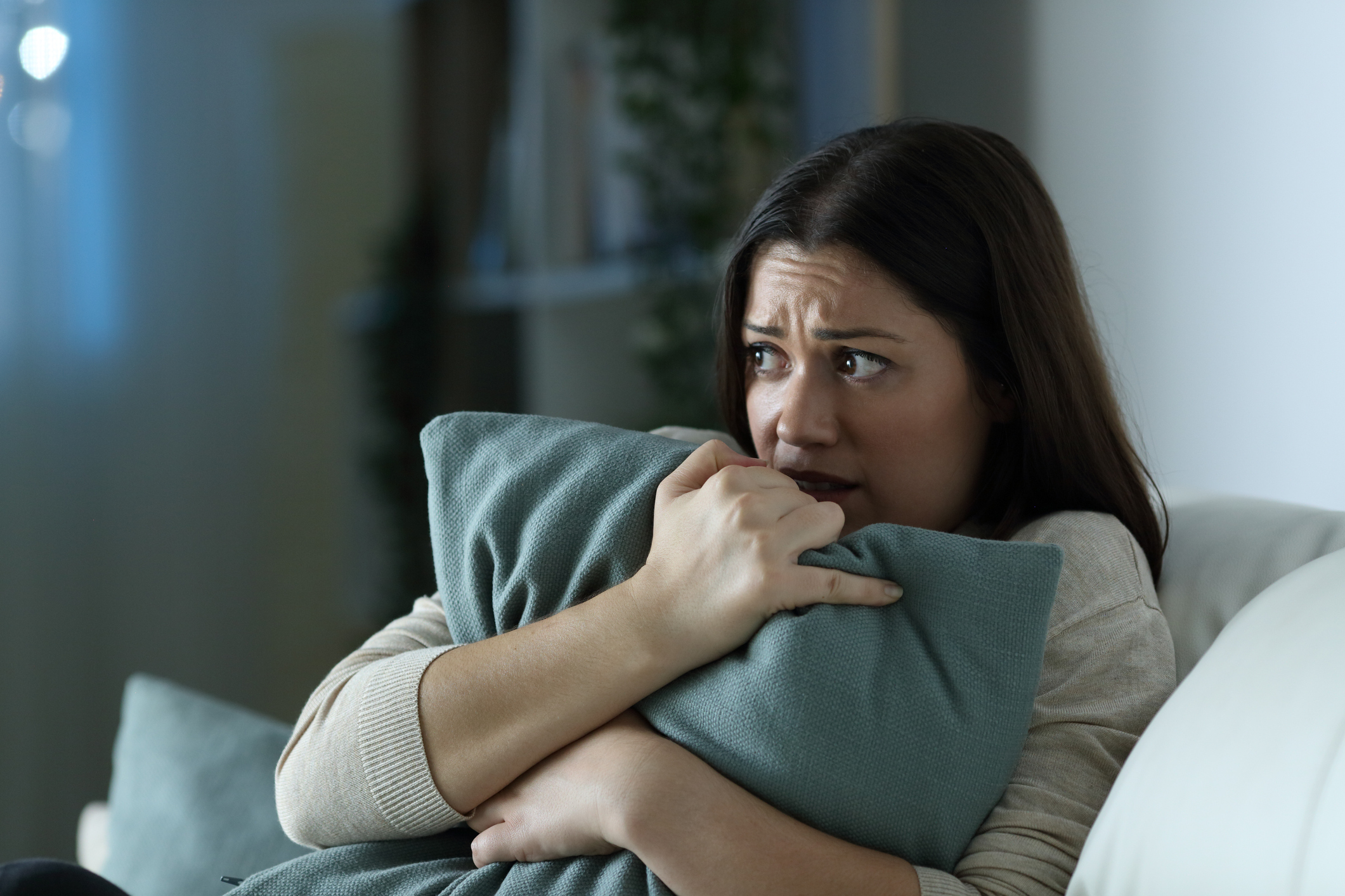 Scared woman embracing pillow at home in the night Scared woman embracing pillow at home in the night